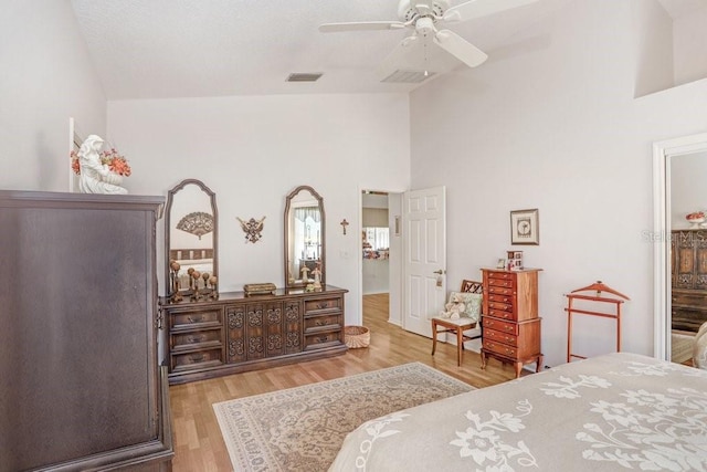 bedroom with ceiling fan, high vaulted ceiling, and light hardwood / wood-style floors