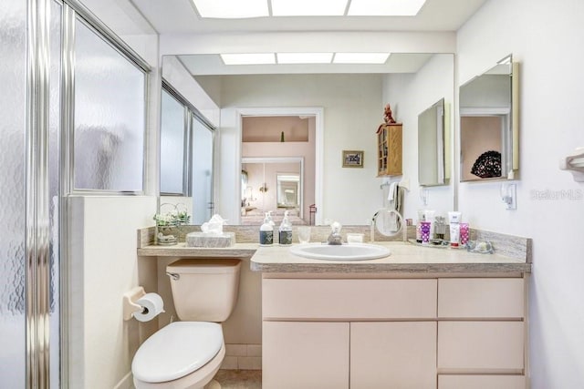 bathroom with an enclosed shower, vanity, and toilet