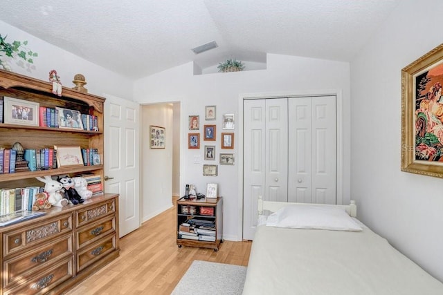 bedroom featuring light hardwood / wood-style floors, lofted ceiling, and a closet