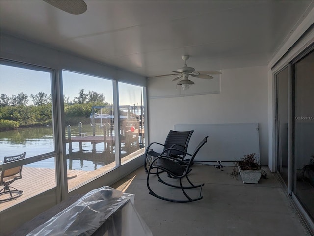 sunroom / solarium featuring ceiling fan and a water view