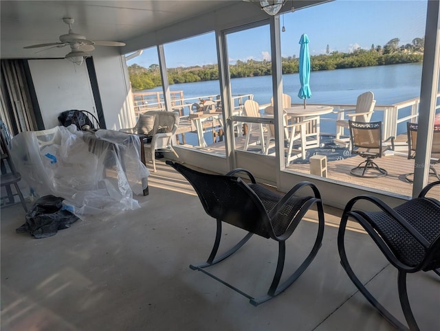 sunroom with a water view and ceiling fan