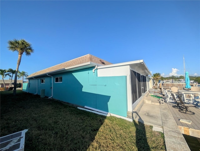 view of side of property with a lawn, a sunroom, central AC unit, and a patio area