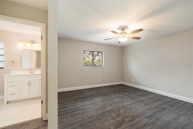 spare room with a textured ceiling, dark hardwood / wood-style floors, ceiling fan, and sink