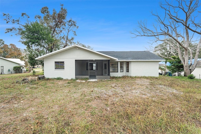 rear view of house featuring a yard and a sunroom