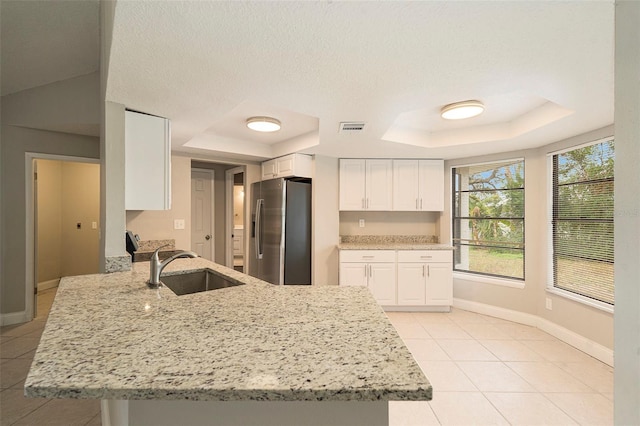 kitchen featuring white cabinetry, sink, a raised ceiling, stainless steel refrigerator with ice dispenser, and kitchen peninsula