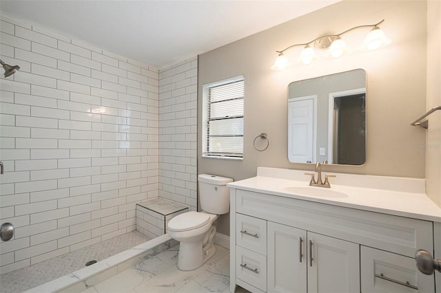 bathroom featuring vanity, toilet, and tiled shower