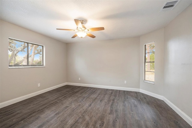 spare room with ceiling fan, plenty of natural light, and dark hardwood / wood-style floors