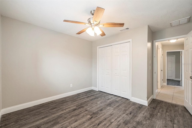 unfurnished bedroom with ceiling fan, a closet, and dark wood-type flooring