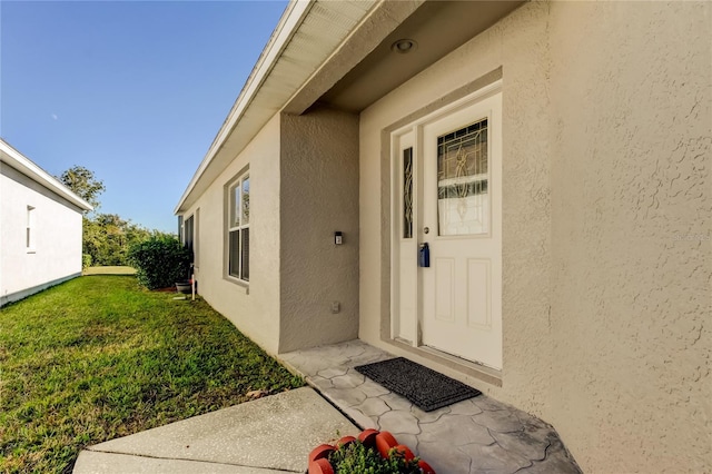 entrance to property featuring a lawn