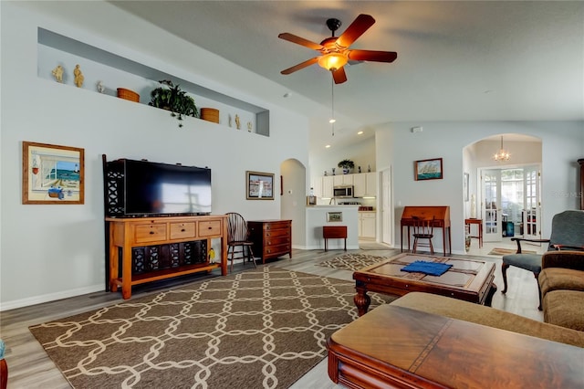 living room with a high ceiling, wood-type flooring, and ceiling fan with notable chandelier