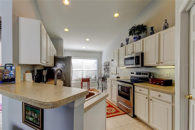 kitchen featuring kitchen peninsula, light tile patterned floors, stainless steel appliances, and white cabinets