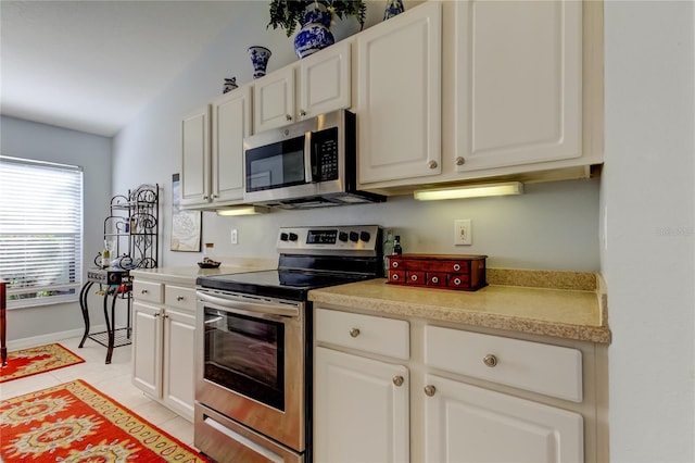 kitchen featuring white cabinets, light tile patterned floors, stainless steel appliances, and vaulted ceiling