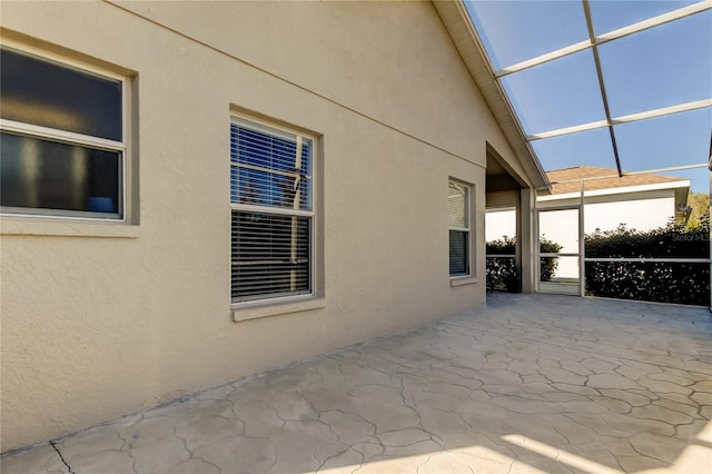 view of property exterior with glass enclosure and a patio area