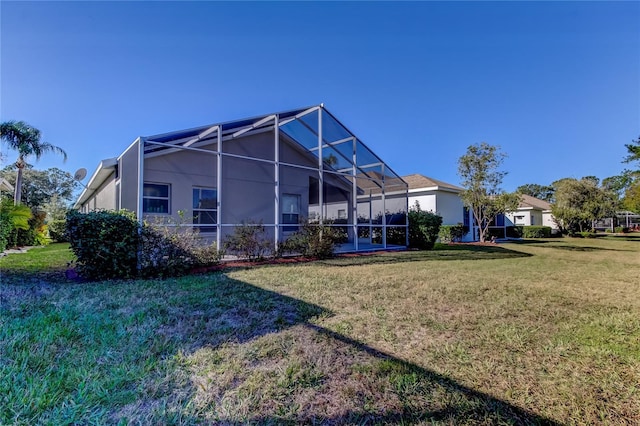 rear view of house featuring glass enclosure and a lawn