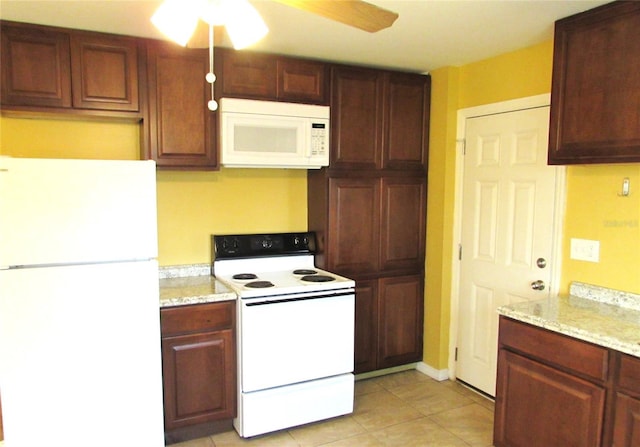 kitchen featuring light stone countertops, light tile patterned floors, white appliances, and ceiling fan