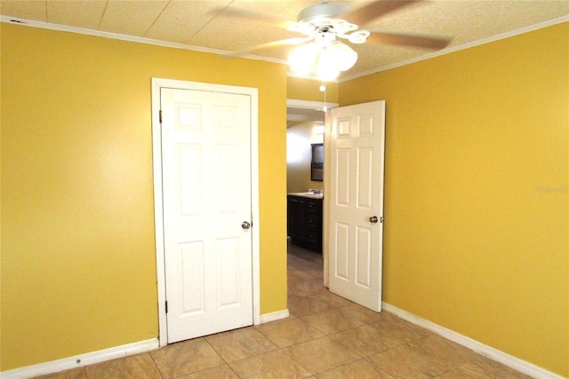 unfurnished bedroom featuring ceiling fan, light tile patterned floors, and ornamental molding