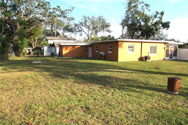 rear view of property with a lawn and central AC