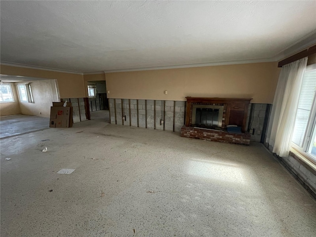 unfurnished living room with crown molding and a brick fireplace