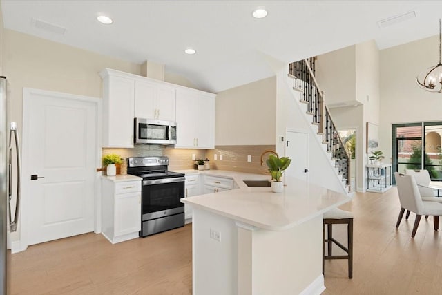 kitchen featuring pendant lighting, white cabinetry, sink, and appliances with stainless steel finishes