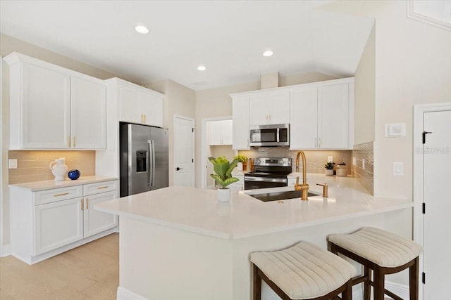 kitchen with white cabinets, kitchen peninsula, stainless steel appliances, and a breakfast bar area