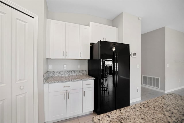 kitchen with light stone countertops, light tile patterned floors, white cabinetry, and black refrigerator with ice dispenser