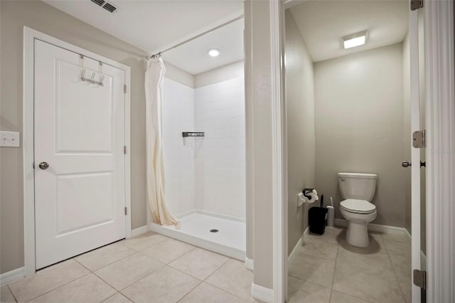 bathroom with a shower with shower curtain, tile patterned flooring, and toilet