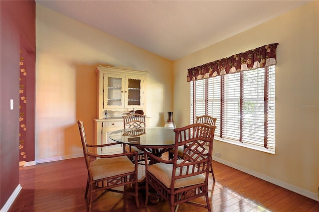 dining space featuring hardwood / wood-style floors and vaulted ceiling