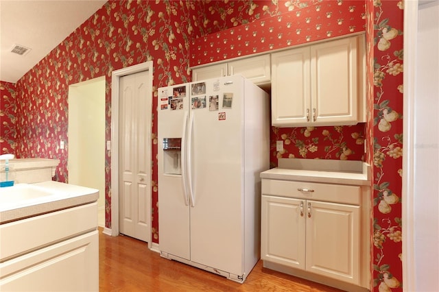 kitchen featuring white fridge with ice dispenser, sink, and light hardwood / wood-style flooring