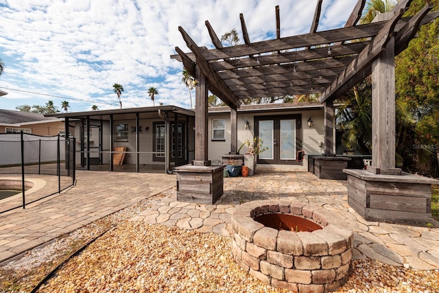 view of patio / terrace featuring a pergola, a sunroom, french doors, and an outdoor fire pit