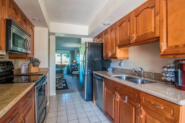 kitchen featuring light stone countertops, sink, light tile patterned flooring, and appliances with stainless steel finishes