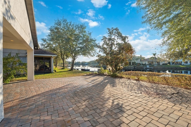 view of patio with a sunroom and a water view