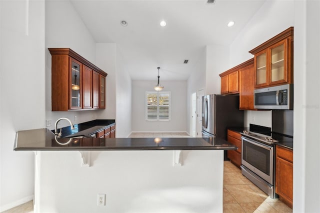 kitchen featuring hanging light fixtures, a breakfast bar, light tile patterned flooring, and stainless steel appliances