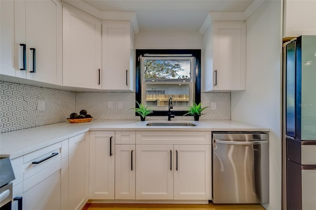 kitchen featuring white cabinets, backsplash, stainless steel dishwasher, and sink