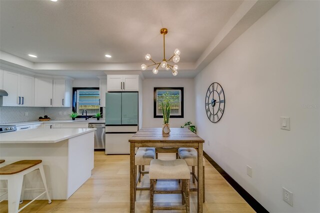 kitchen with dishwasher, white fridge, pendant lighting, white cabinets, and light wood-type flooring