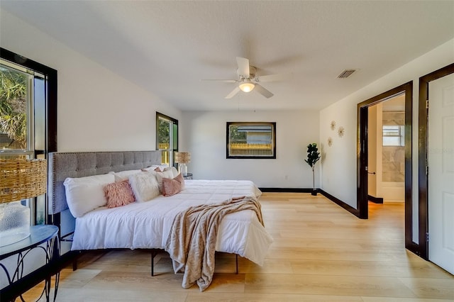 bedroom with light hardwood / wood-style floors, ensuite bath, and ceiling fan