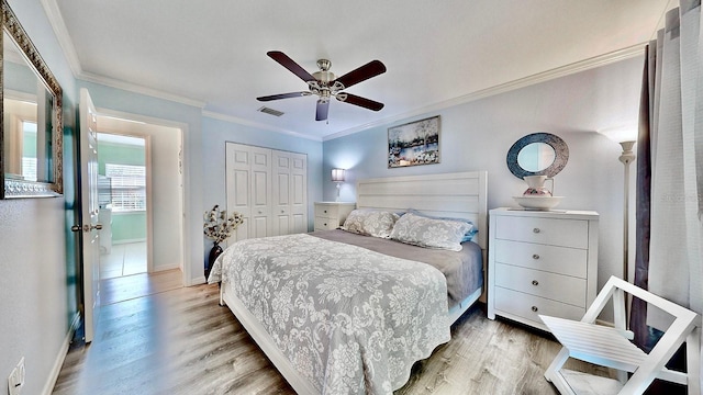 bedroom with hardwood / wood-style floors, ceiling fan, ornamental molding, and a closet