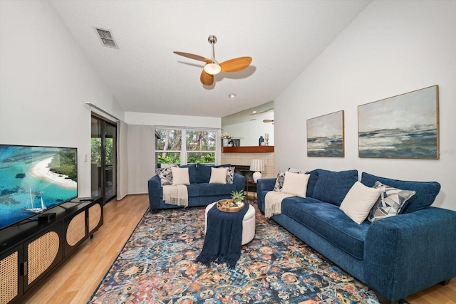 living room featuring ceiling fan, light hardwood / wood-style floors, and a textured ceiling