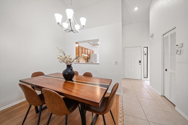 dining area featuring a chandelier, a towering ceiling, and light tile patterned flooring