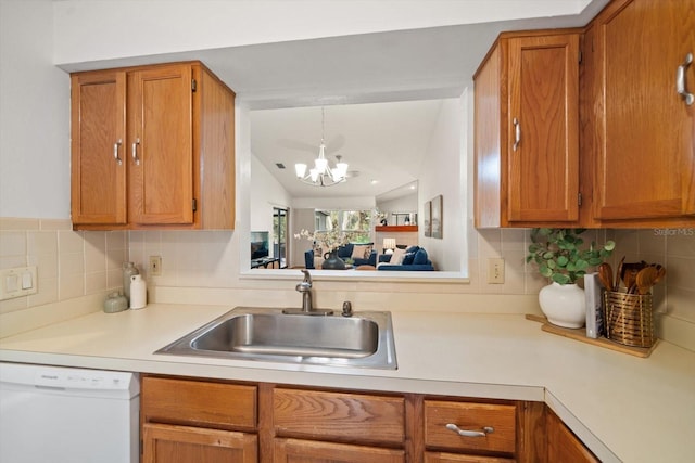 kitchen with backsplash, white dishwasher, vaulted ceiling, sink, and an inviting chandelier