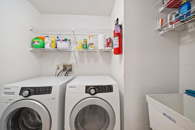 laundry room with a textured ceiling, separate washer and dryer, and sink