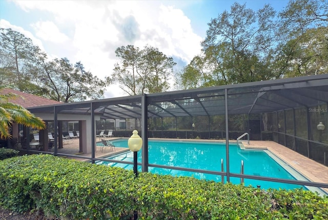 view of pool with glass enclosure and a patio area