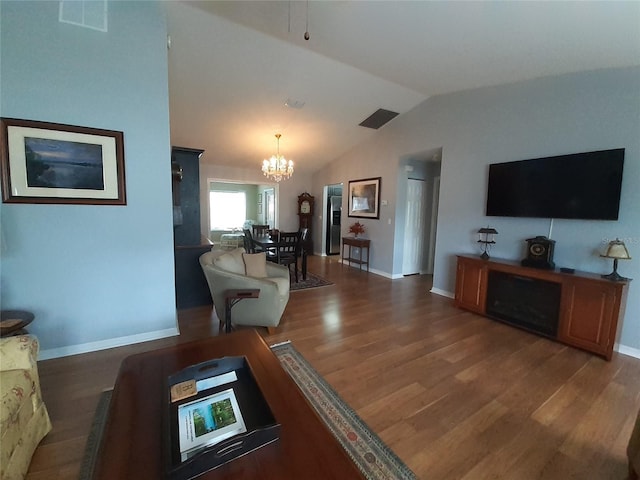 living room with dark hardwood / wood-style flooring, an inviting chandelier, and lofted ceiling