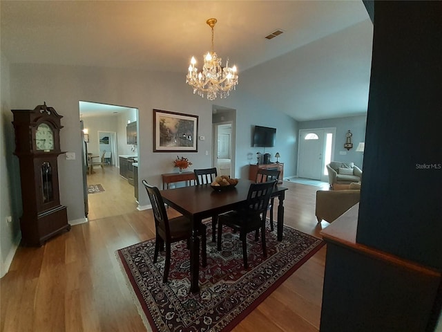 dining space featuring light wood-type flooring, lofted ceiling, and a chandelier