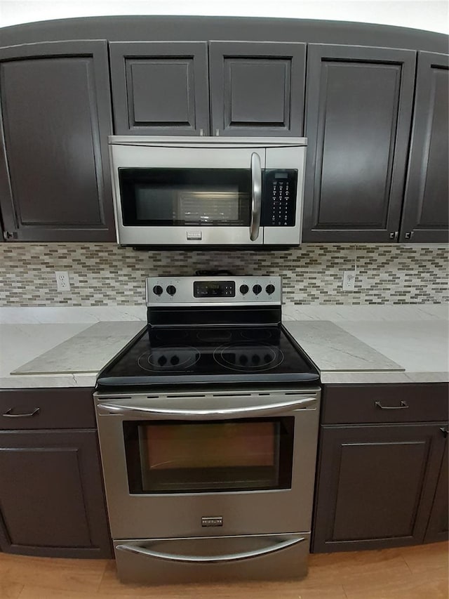 kitchen with appliances with stainless steel finishes, tasteful backsplash, and light stone counters