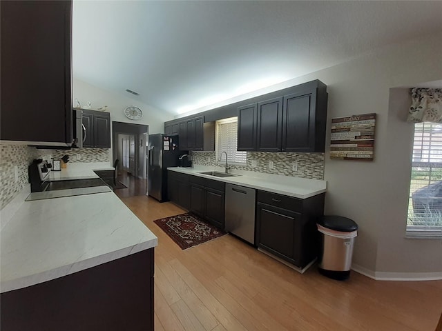 kitchen featuring refrigerator, stainless steel dishwasher, sink, range, and lofted ceiling