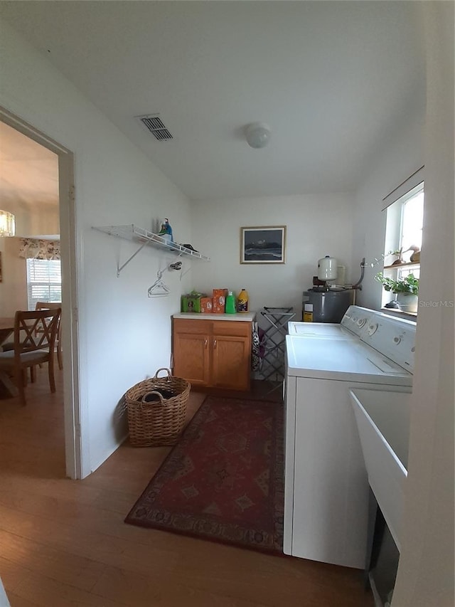 laundry room with dark hardwood / wood-style flooring, washer and dryer, and cabinets