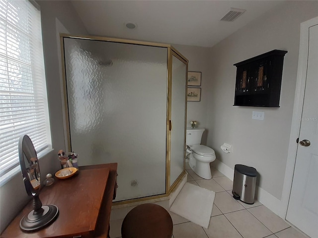 bathroom featuring tile patterned flooring, a shower with door, and toilet