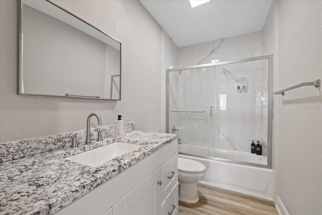 full bathroom featuring combined bath / shower with glass door, wood-type flooring, vanity, and toilet