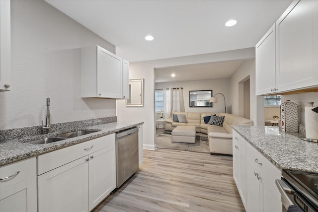 kitchen with light stone countertops, sink, white cabinets, and stainless steel dishwasher