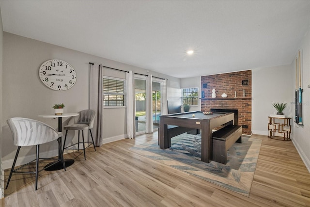 rec room with pool table, light hardwood / wood-style floors, and a brick fireplace